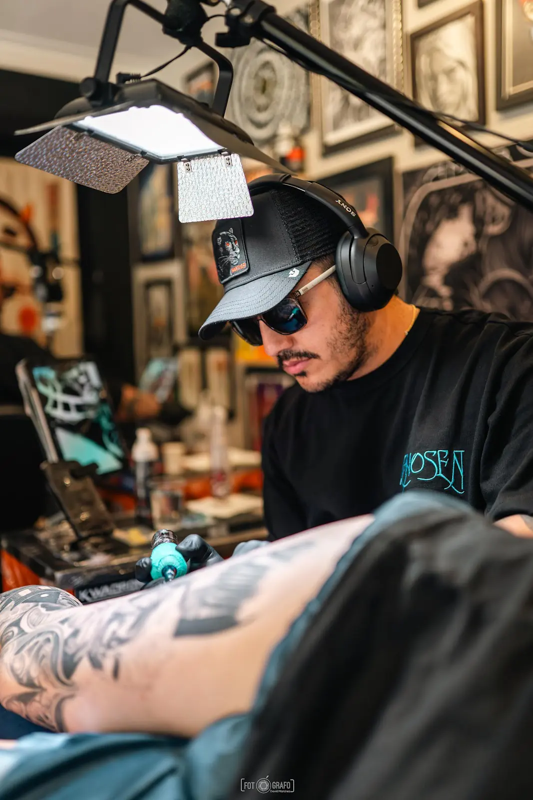Tatuador de Ópalo trabajando en un brazo bajo la lámpara del estudio